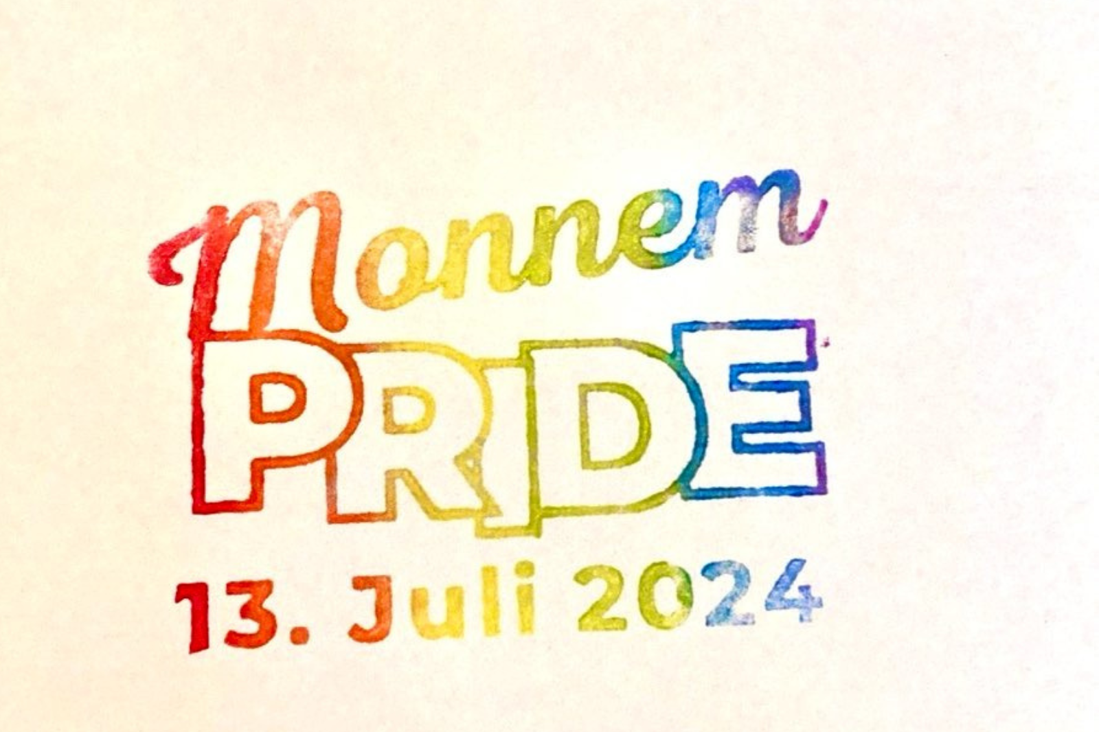 Auf dem Bild ist ein regenbogen-farbener Stempel zu sehen, auf dem "Monnem PRIDE 13. Juli 2024" steht. Der Hintergrund ist creme-farben.