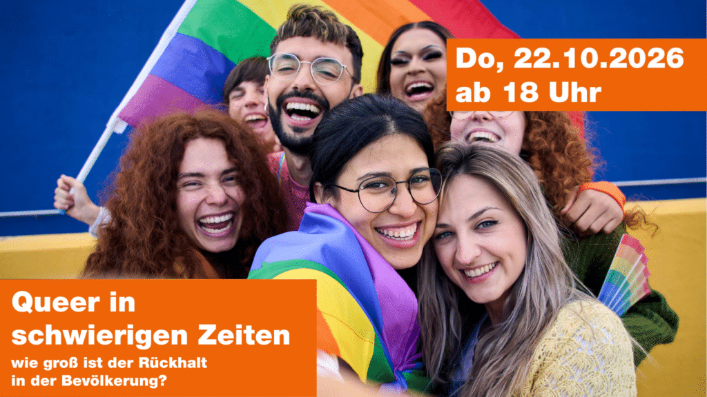 Eine Gruppe Personen lächeln in die Kamera und halten eine Regenbogenflagge.